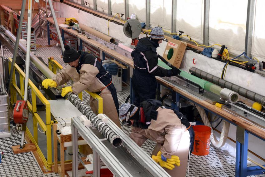 Science team members work in the South Pole Ice Core drill tent, cleaning the drill and measuring ice cores