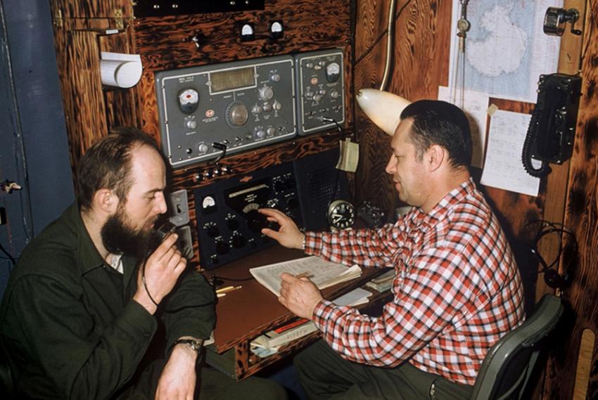 Charles Bentley, left, uses a ham radio while sitting next to station leader Steve Barnes at Byrd Station during his second winter of the International Geophysical Year