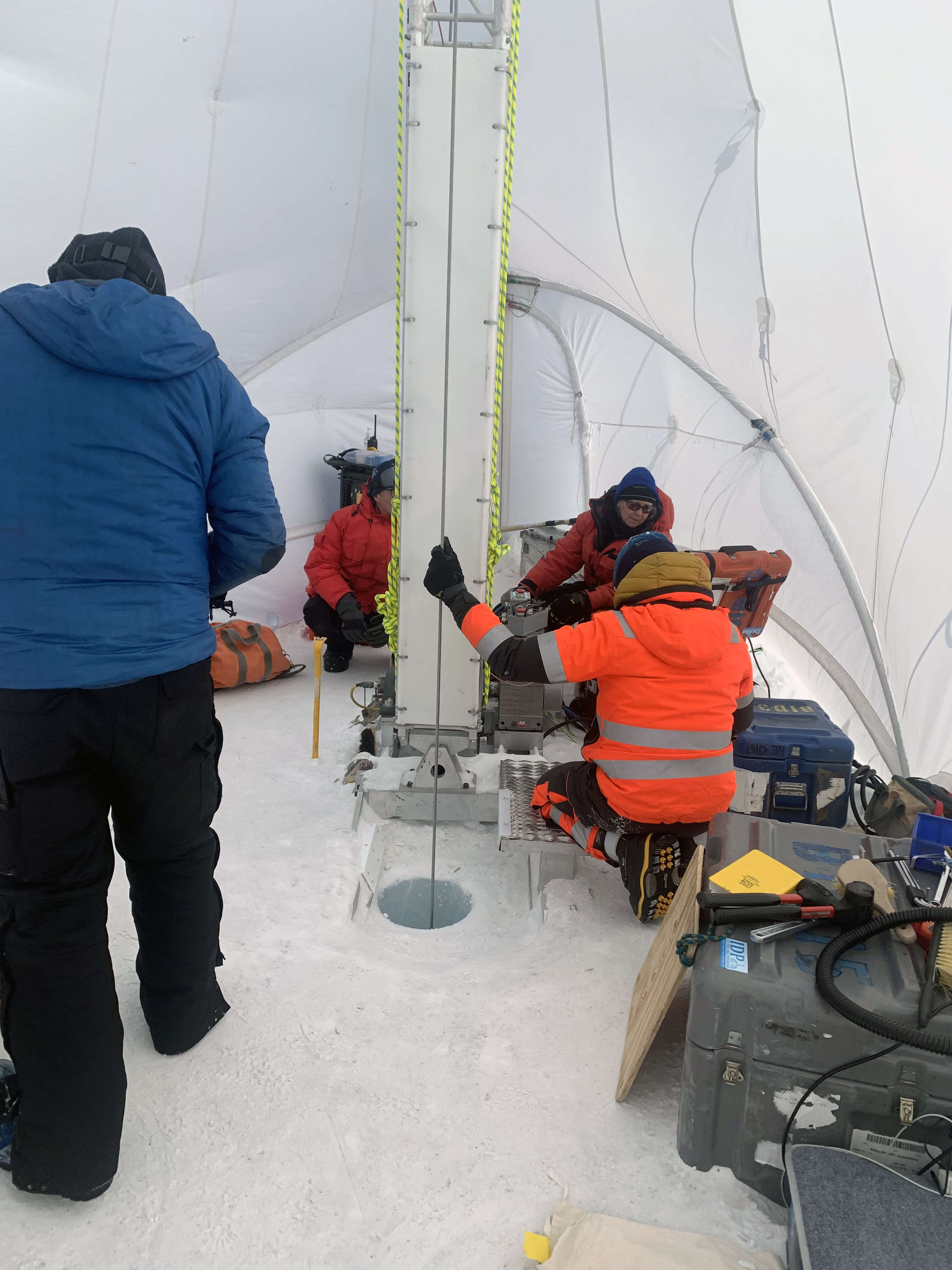 Elizabeth Morton (red jacket and sunglasses) and Andrew Haala (orange jacket) operate the Blue Ice Drill (BID) at Allan Hills, Antarctica. Credit: Jenna Epifanio/NSF COLDEX.